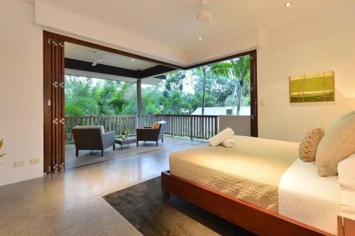 1 dormitorio con 1 cama y balcón en 6 Beachfront Mirage - Luxury 4 Bedroom Home, en Port Douglas