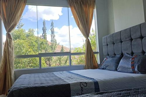 een bed in een slaapkamer met een groot raam bij Qori Garden Apartment in Cuzco