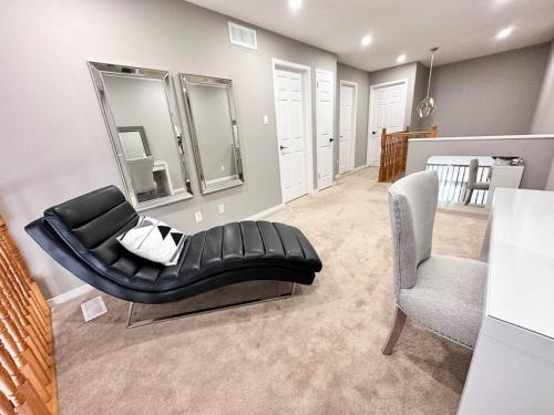 B’s King Suite في أوتاوا: أريكة جلدية سوداء وكرسي في الغرفة