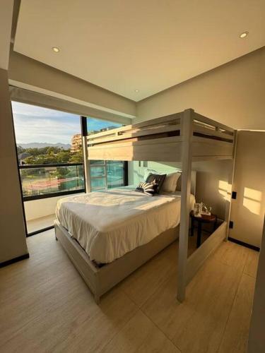 a bedroom with a bunk bed and a large window at Departamento Bucerías con Vista al Mar - Narval Norte in Bucerías