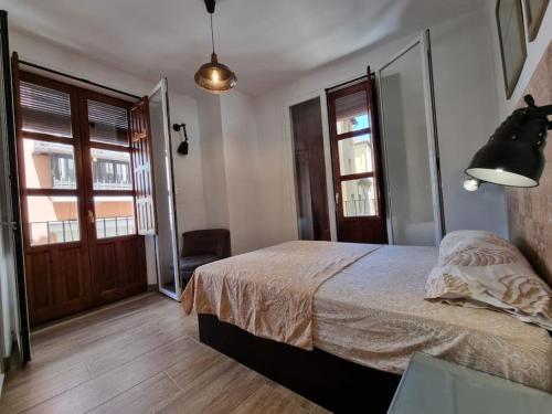 a bedroom with a bed and two windows at Exclusividad a Pie de la Torre de la Catedral in Granada