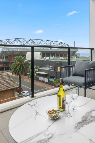 a table with two glasses and a bottle of wine on a balcony at Burelli Beach Escape - Breezy Seaside Charm in Wollongong