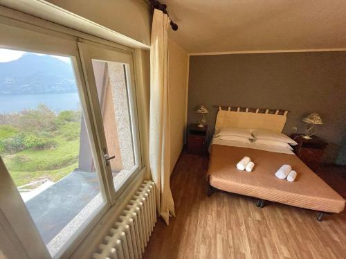 a bedroom with a bed and a large window at Hotel Ristorante La Sorgente in Plesio