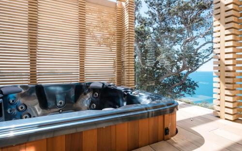 a bath tub in a room with a large window at Onetangi Belle - Coast & Country in Onetangi