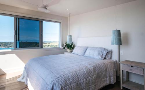 a bedroom with a bed and a large window at Onetangi Belle - Coast & Country in Onetangi