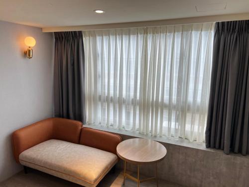 a living room with a couch and a table in front of a window at MU House in Taipei