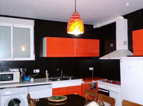 d'une cuisine avec des armoires orange et un éclairage d'ambiance. dans l'établissement El Mirador de Pablo, casa con patio privado, à Alomartes