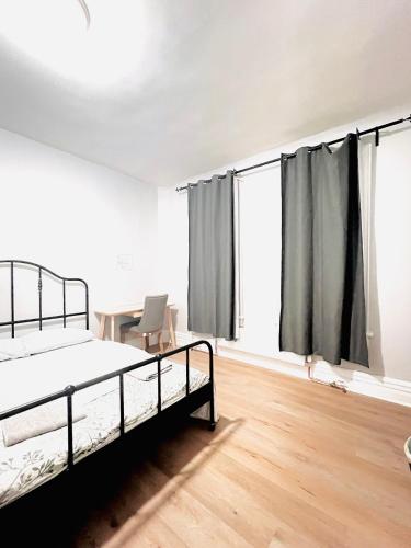 um quarto vazio com uma cama, uma secretária e janelas em O Canada Guest House em Toronto