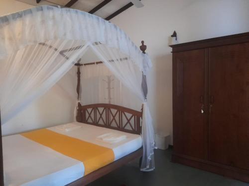 a bedroom with a canopy bed and a wooden cabinet at Sanuki Villa in Hikkaduwa