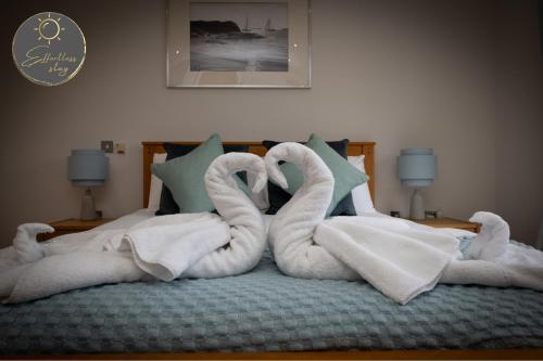 een bed met twee zwanen gemaakt van handdoeken bij Salterns Rest - Luxury, Spacious, Business, Leisure or Groups, Sleeps 9, Parking, Moments from Harbour, Dog Friendly in Poole