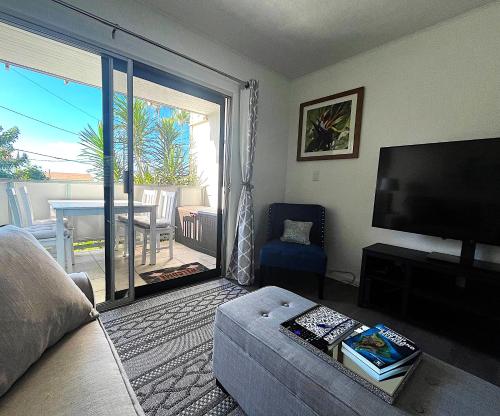 a living room with a large sliding glass door to a patio at Your Slice of Paradise in Kona - Walk to Beach and Stores in Kailua-Kona