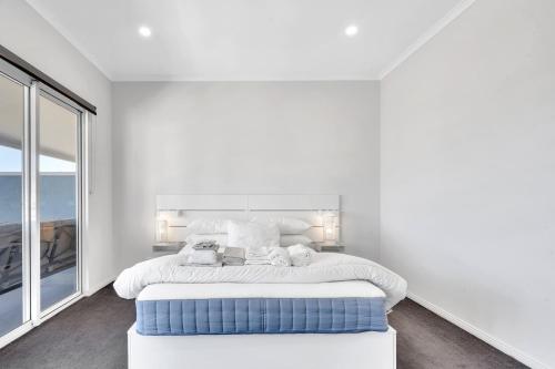a white bedroom with a large bed and a window at 96B Esplanade, Semaphore in Semaphore
