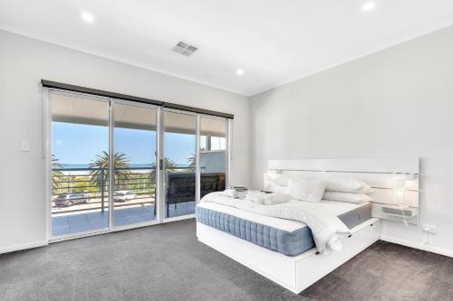 a white bedroom with a bed and a balcony at 96B Esplanade, Semaphore in Semaphore