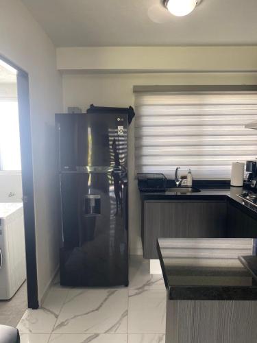 a kitchen with a large black refrigerator in a room at Apartamento en planta baja in Acapulco