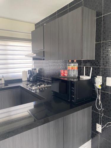 a kitchen with a black counter top with a microwave at Apartamento en planta baja in Acapulco