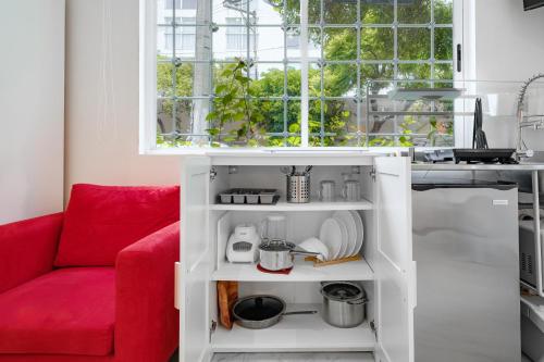 a red couch in a white kitchen with a window at Leib 65 in Mexico City