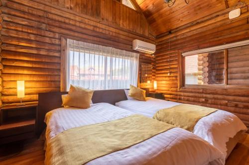 two beds in a room with wooden walls at Goto Conkana Kingdom in Goto