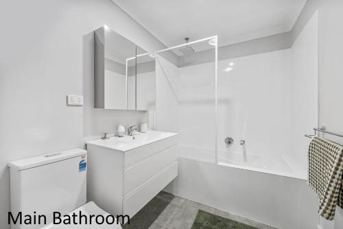a white bathroom with a sink and a shower at Little Mirror Bay in Laurieton
