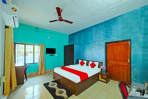 Schlafzimmer mit blauen Wänden, einem Bett und einem Deckenventilator in der Unterkunft Hotel Madison Homes Bhubaneswar Near Lingaraj Temple and Ram Mandir in Bhubaneshwar