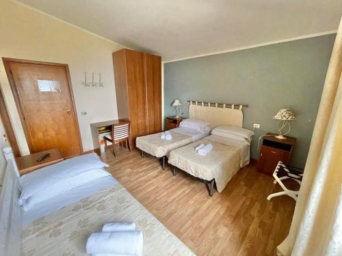 a bedroom with two beds and a table with a lamp at Hotel Ristorante La Sorgente in Plesio