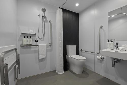 a bathroom with a shower and a toilet and a sink at Abstract Hotel in Auckland