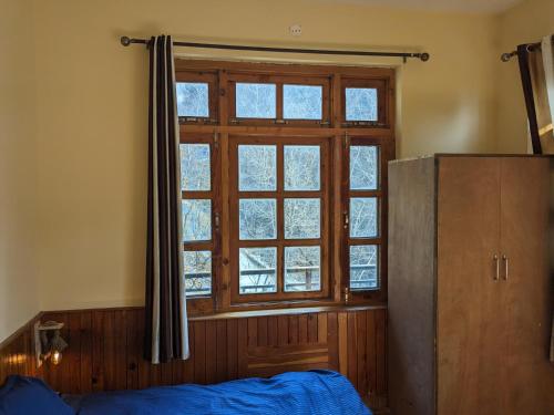 Nagar的住宿－Emma stays，卧室设有窗户,前面设有一张蓝色的床。