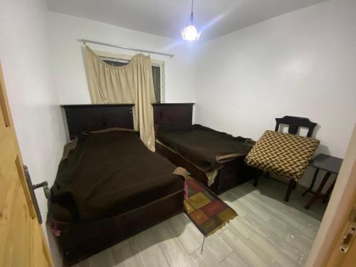 um quarto com duas camas e uma cadeira em Moon no Cairo