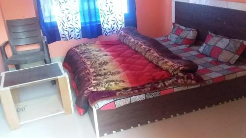a bedroom with a bed and a chair in it at SPOT ON Sharma's Kitchen & Home Stay in Bajaura