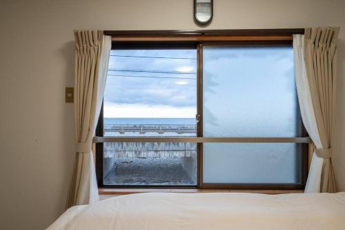a bedroom with a window with a view of the ocean at Seaside House Nagi in Itoigawa