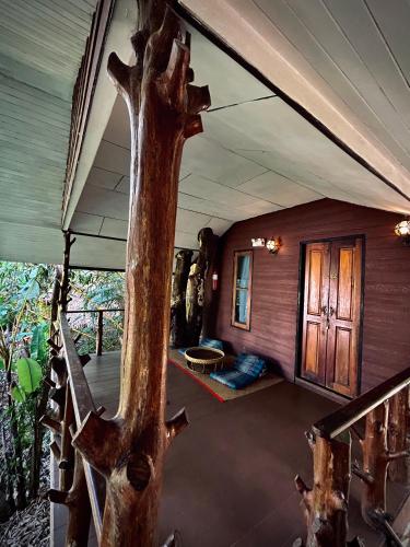 a porch of a house with a tree trunk at Khao Sok Paradise Resort in Khao Sok National Park