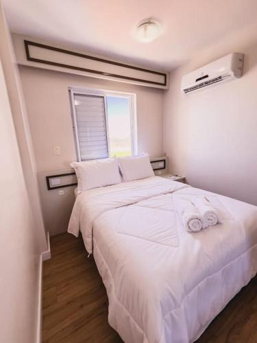 a bedroom with a large white bed and a window at Apto novo com vista para o mar e piscina in Laguna