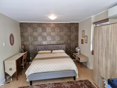 a bedroom with a bed and a desk and a window at Entire ground floor with full-privacy and family-friendly popular to ferry catchers in Wellington