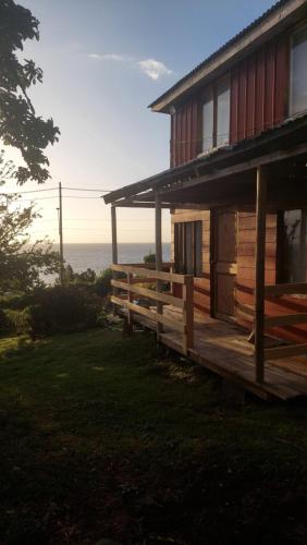 a wooden house with the ocean in the background at Cabaña Frente Al mar, Carretera Austral km 38,6, Puerto Montt in Puerto Montt