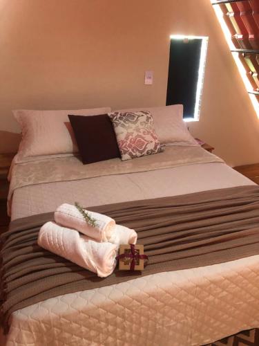 a bed with a cross and towels on it at Chalé das Montanhas in Caparaó Velho