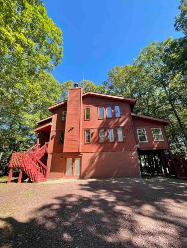 uma grande casa vermelha com uma escada em frente em Poconos Chalet -Kayaks- HotTub-Karaoke-Lake em East Stroudsburg