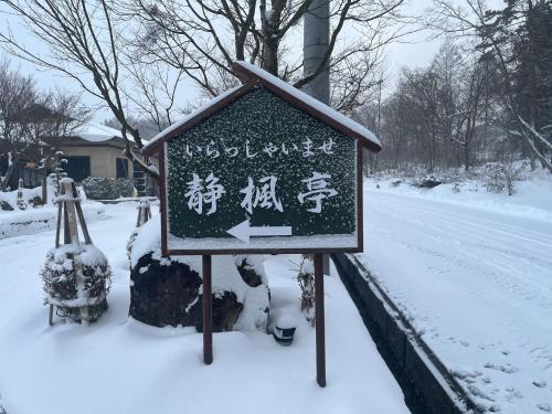 a sign in the snow next to a street at Seifutei in Inawashiro