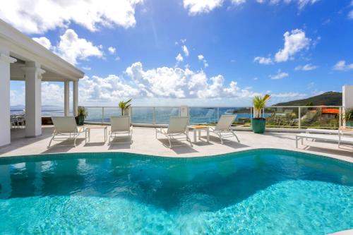 a swimming pool with chairs and a view of the ocean at Oceanview Luxury Villa Escape in Dawn Beach