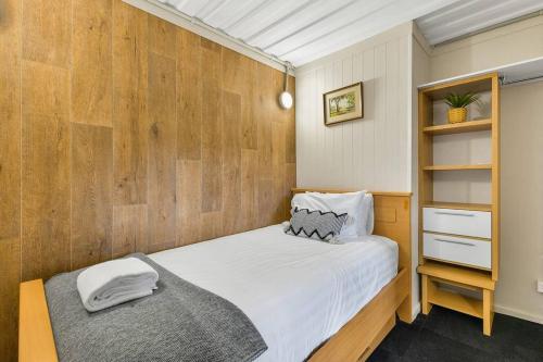 a bedroom with a bed and a wooden wall at The Bunker - Orange, NSW in Mullion Creek