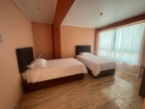 2 Betten in einem Zimmer mit Fenster in der Unterkunft Cardos hostal in Pisco