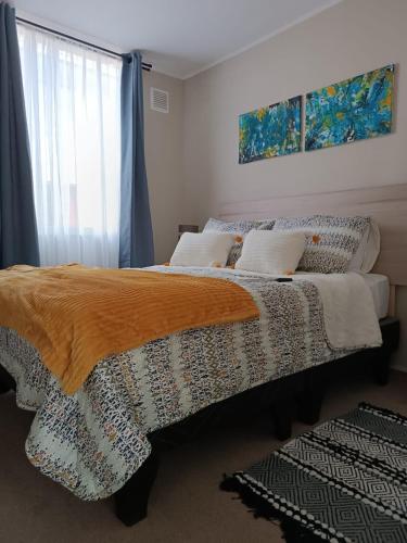 una camera da letto con un letto con una coperta e una finestra di Departamento Ovalle 305 Quipu a Ovalle