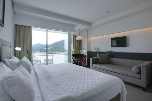 a hotel room with a large bed and a couch at Sugar Palm Grand Hillside - SHA Plus in Kata Beach