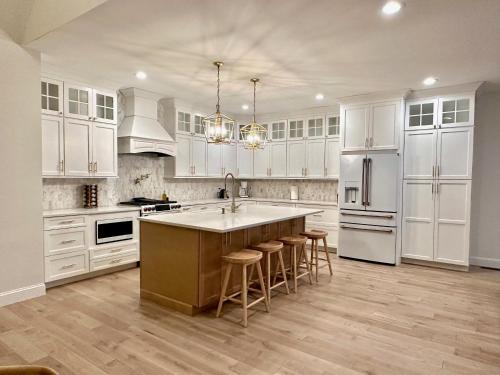 a kitchen with white cabinets and a kitchen island with bar stools at New Farmhouse, King Beds, Game Room, Hot Tub & View! in Montgomery