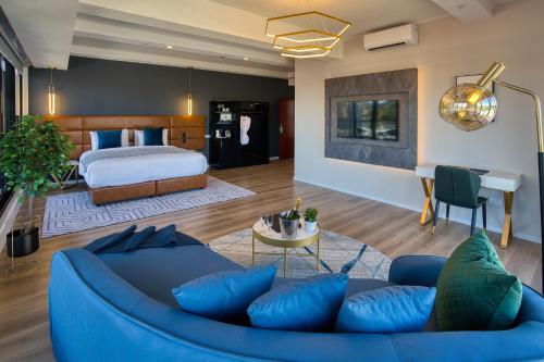 SOHO Hotel Auckland في أوكلاند: غرفة معيشة مع أريكة زرقاء وسرير