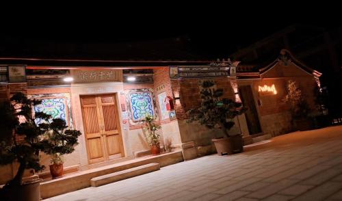 a building with a wooden door and some plants on it at Ba Ba Guan Hai Ancient House B&B in Jinsha