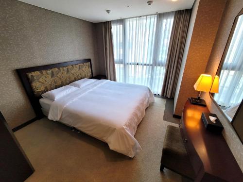 sypialnia z białym łóżkiem i oknem w obiekcie W Residence Hotel Centum City w Pusanie