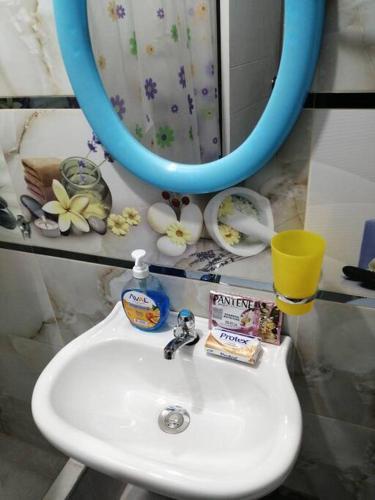 a bathroom sink with a blue mirror and a mirror at Huascarán wasi, cómodo, con wifi y ducha caliente in Huaraz
