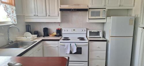 a white kitchen with a stove and a sink at Seaview property Hastings Towers 3D-Studio Apt in Bridgetown
