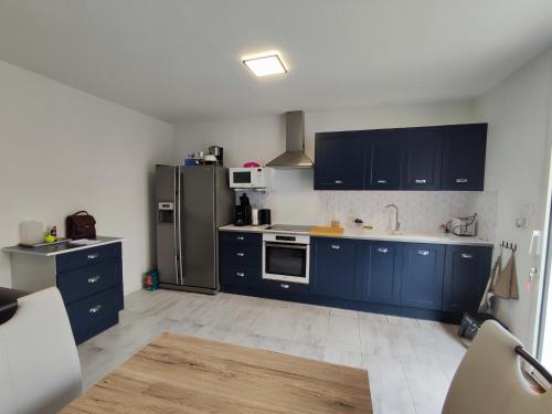 La cuisine est équipée de placards bleus et d'un réfrigérateur en acier inoxydable. dans l'établissement Villa rénovée avec clim et terrasse à 150m de la plage - FR-1-776-3, à Argelès-sur-Mer