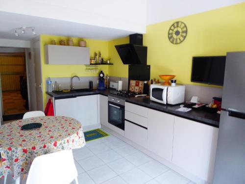 d'une cuisine avec des placards blancs et des murs jaunes. dans l'établissement Pavillon climatisé 4/5 pers, grande terrasse, proche plage et commerces, parking sécurisé - FR-1-776-6, à Argelès-sur-Mer