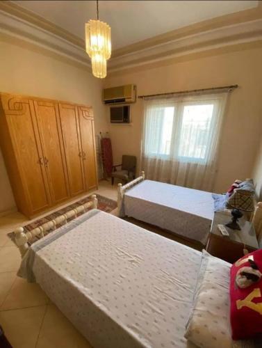 een slaapkamer met 2 bedden en een kroonluchter bij Heshamm Hamzaa in Caïro